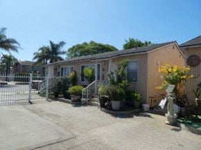Oxnard apartment for rent - a small building with a white gate and plants in front of it
