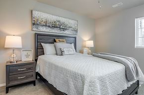 Saukville apartment for rent - A bedroom with a large bed, a nightstand with a lamp, and a framed picture on the wall.
