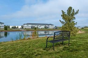 Plover apartment for rent - A bench with a metal armrest and a decorative design on the backrest is situated on a grassy area next to a body of water.