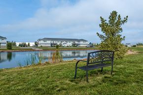 Plover apartment for rent - A bench with a metal armrest and a decorative design on the backrest is situated on a grassy area next to a body of water.