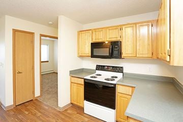 Newton apartment for rent - A kitchen with wooden cabinets and a black microwave above the stove.