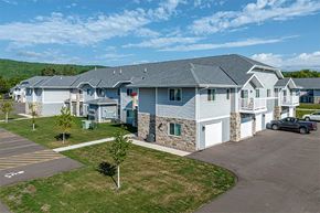 Duluth apartment for rent - A large building with a grey roof and a parking lot in front.