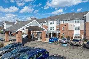 Alliance apartment for rent - A parking lot in front of a multi-story building with cars parked.