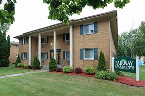Manitowoc apartment for rent - an apartment building with a yard and a sign for fairway apartments