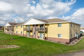 Stevens Point apartment for rent - a yellow apartment building with a green yard and a cloudy sky