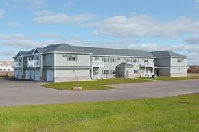 Beaver Dam apartment for rent - A large grey building with a parking lot in front.