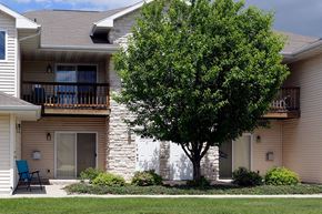 Green Bay apartment for rent - A tree in front of a tan building with a white fence.