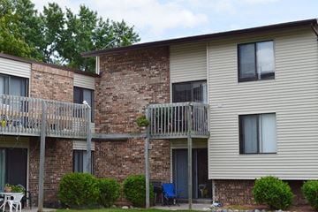 Appleton apartment for rent - A balcony with a chair and table is on the left side of a brick building.