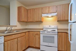 Little Chute apartment for rent - A kitchen with wooden cabinets and white appliances.