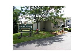 Sheboygan Falls apartment for rent - A sign for Windsor Village Apartments stands in front of a building.