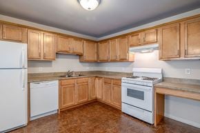 Alliance apartment for rent - A kitchen with wooden cabinets and a white refrigerator.