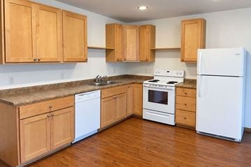 Viroqua apartment for rent - A kitchen with wooden cabinets and white appliances.