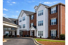 Sumter apartment for rent - A large white and brick building with a covered walkway.
