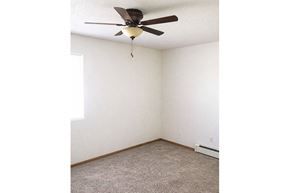 Oskaloosa apartment for rent - A room with a ceiling fan and carpeted floor.
