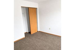 Sleepy Eye townhouse for rent - A room with a carpeted floor and a wooden door.