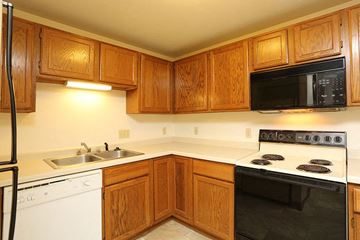 Appleton apartment for rent - A kitchen with wooden cabinets and a black microwave above the stove.
