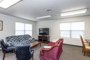 Lawrence apartment for rent - A living room with a grey sofa, a blue chair, a pink couch, and a television.