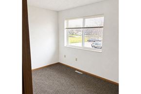 Sleepy Eye townhouse for rent - A room with a window showing a view of a parking lot and trees.