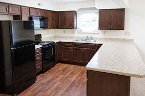 Knightstown apartment for rent - A kitchen with dark wood cabinets and a black refrigerator.
