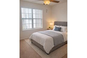 Sumter apartment for rent - A bedroom with a bed, a ceiling fan, and a window.