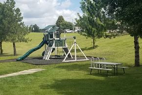 Atlantic apartment for rent - A playground with a green slide and picnic tables.