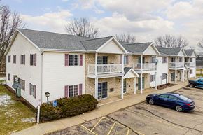 Stevens Point apartment for rent - A white building with a blue car parked in front.
