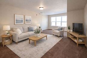 Winfield apartment for rent - A living room with a grey couch, a white chair, a wooden coffee table, and a flat screen TV.