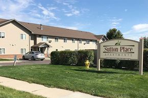 Yankton apartment for rent - A sign for Sutton Place Apartments stands in front of a building.