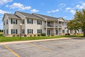 Manitowoc apartment for rent - A large two-story apartment building with a parking lot in front.