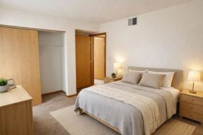 Marshalltown apartment for rent - A bedroom with a bed, nightstand, and a plant on the nightstand.