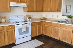 Albert Lea townhouse for rent - A white stove is in a kitchen with wooden cabinets.