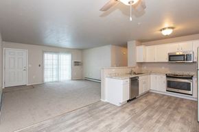 Waupaca apartment for rent - A spacious kitchen with white cabinets and appliances, a ceiling fan, and a window with blinds.