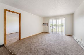 Oskaloosa apartment for rent - A room with a carpeted floor and a window with blinds.