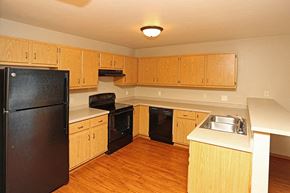 Rhinelander apartment for rent - an empty kitchen with black appliances and wooden cabinets