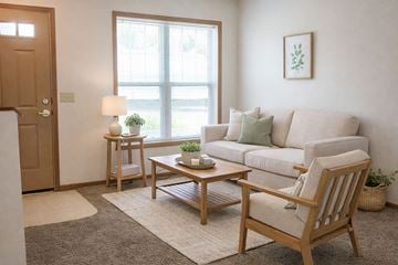 Albert Lea townhouse for rent - A living room with a white couch, a wooden chair, and a small table with a plant on it.