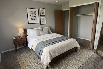 Bluffton apartment for rent - A bedroom with a large bed and a nightstand with a lamp.