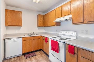 Oskaloosa apartment for rent - A kitchen with wooden cabinets and a white stove top oven.