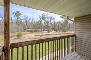 Stevens Point apartment for rent - A wooden deck overlooks a grassy area with trees in the distance.