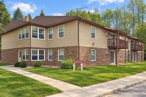 Manitowoc apartment for rent - A brick building with a red sign in front.