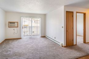 Oskaloosa apartment for rent - A room with a carpeted floor, a door, and a window with a view of a balcony.