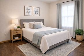 Hays apartment for rent - A bedroom with a large bed and a nightstand with a lamp.
