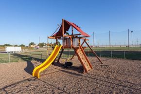 Liberal apartment for rent - a swing set with a yellow slide in a playground