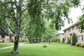 Manitowoc apartment for rent - a large yard with trees in front of a building