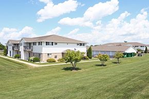 Kaukauna apartment for rent - A large white building with a brown roof and a green lawn in front.