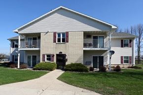 Manitowoc apartment for rent - A two-story house with a white exterior and red shutters.