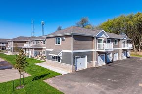 Shawano apartment for rent - A large building with a parking lot in front of it.
