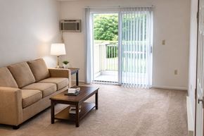 Galesburg apartment for rent - A living room with a couch, a coffee table, and a sliding glass door.