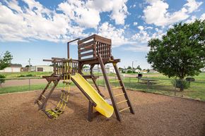 Hugoton apartment for rent - A wooden playground structure with a yellow slide.