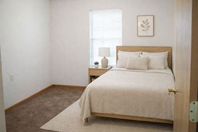 Hays apartment for rent - A bedroom with a bed, nightstand, and lamp.
