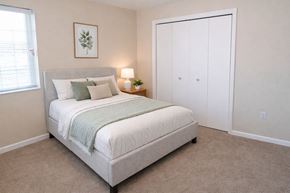 Chanute apartment for rent - A bedroom with a bed, nightstand, and a plant.